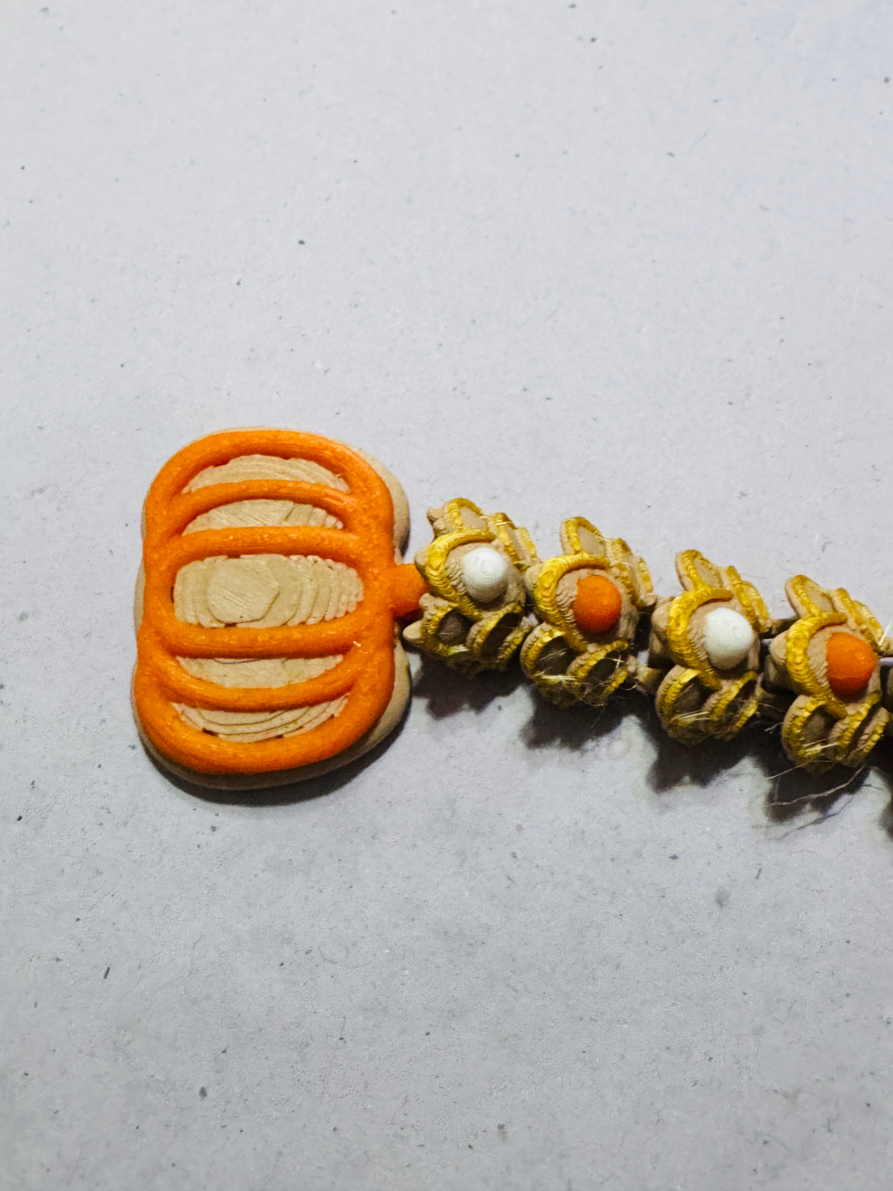 Close-up of articulated dragon body showing smooth 3D printed layers and joint movement in pumpkin-themed colors