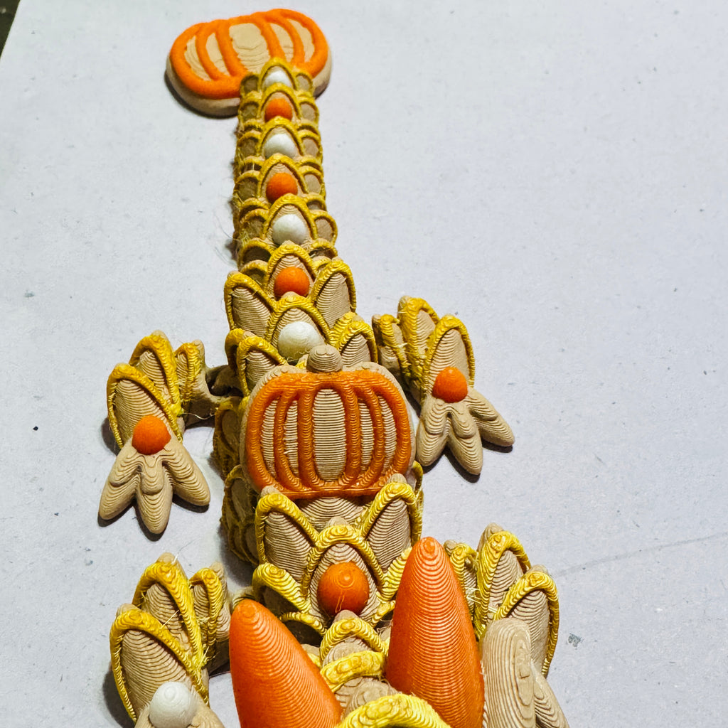 Close-up of articulated dragon body showing smooth 3D printed layers and joint movement in pumpkin-themed colors