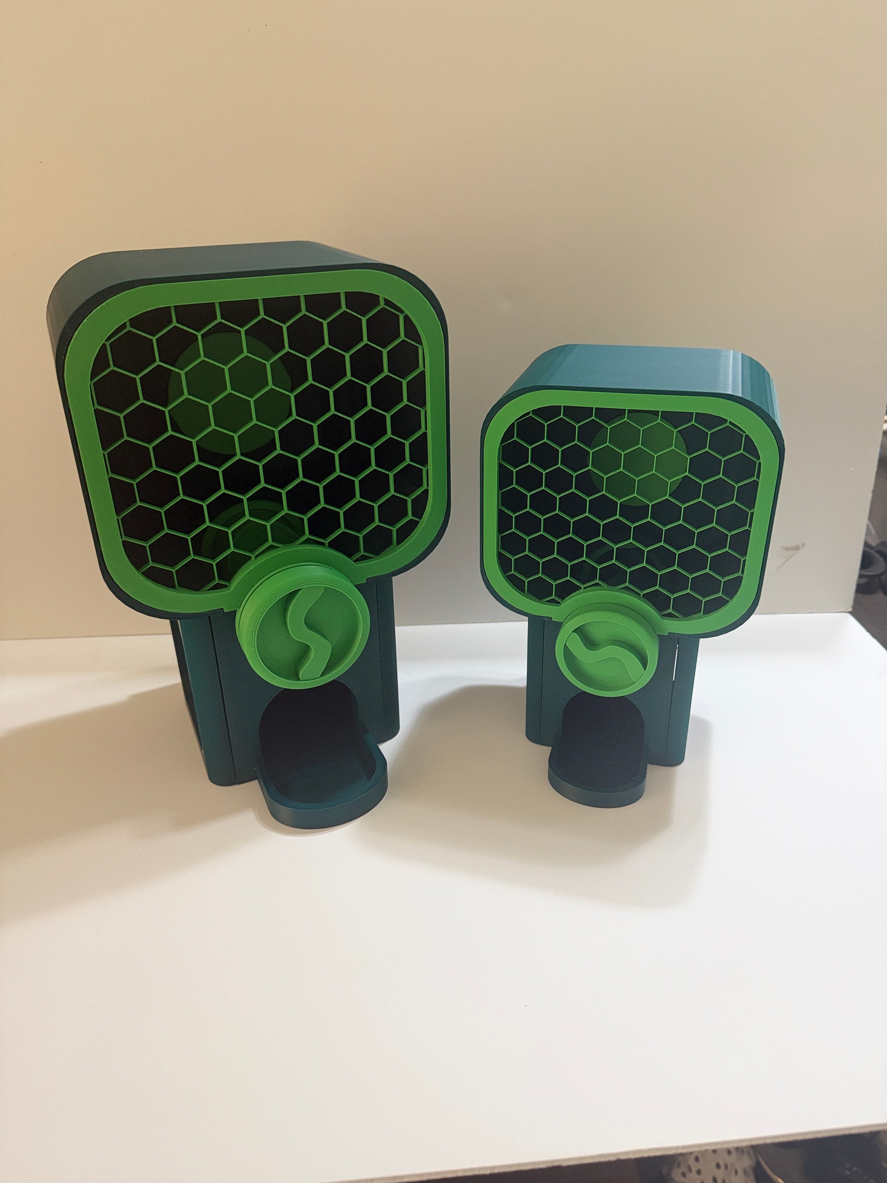 Two green and black pet grooming tools on a white surface with a beige background